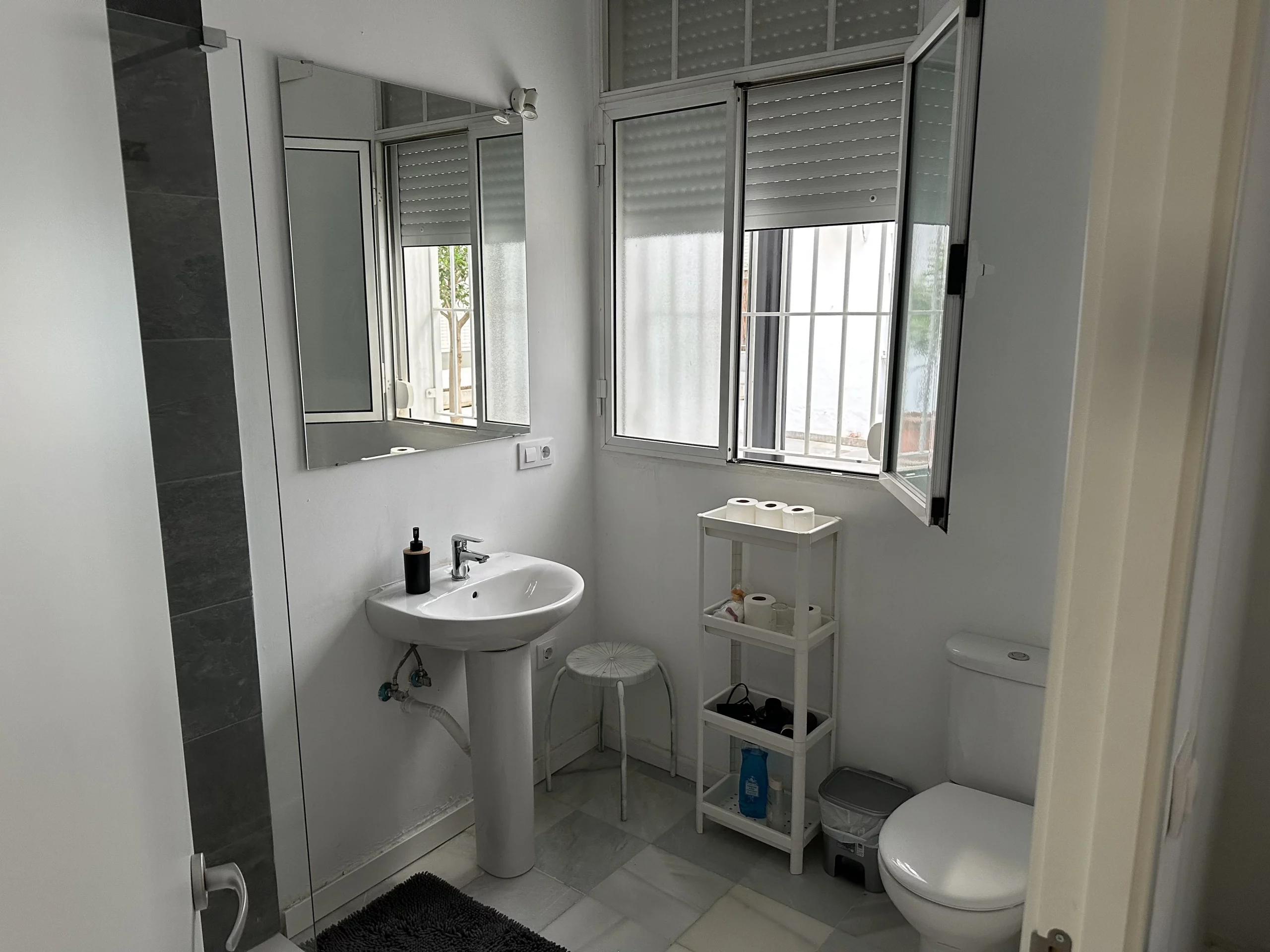 Baño del Apartamento 2 con lavabo, ducha, inodoro y ventana.