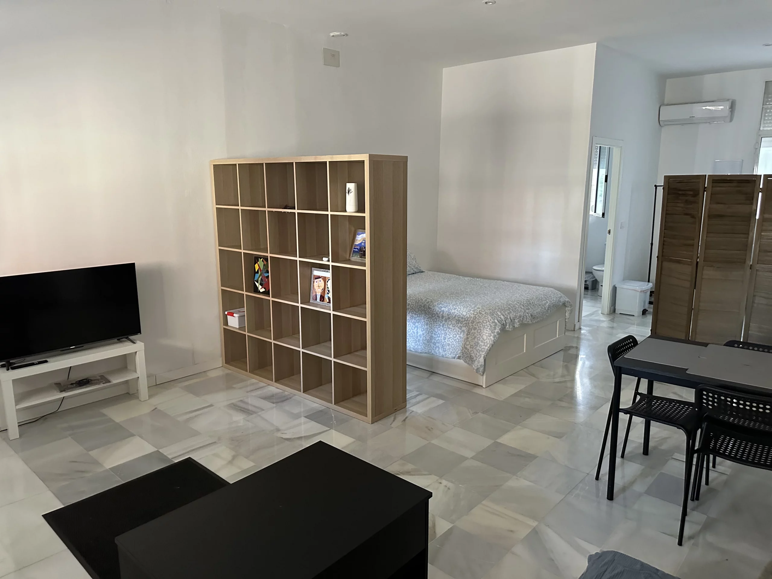 Vista general del Apartamento 2 con salón, cama, comedor y estantería.